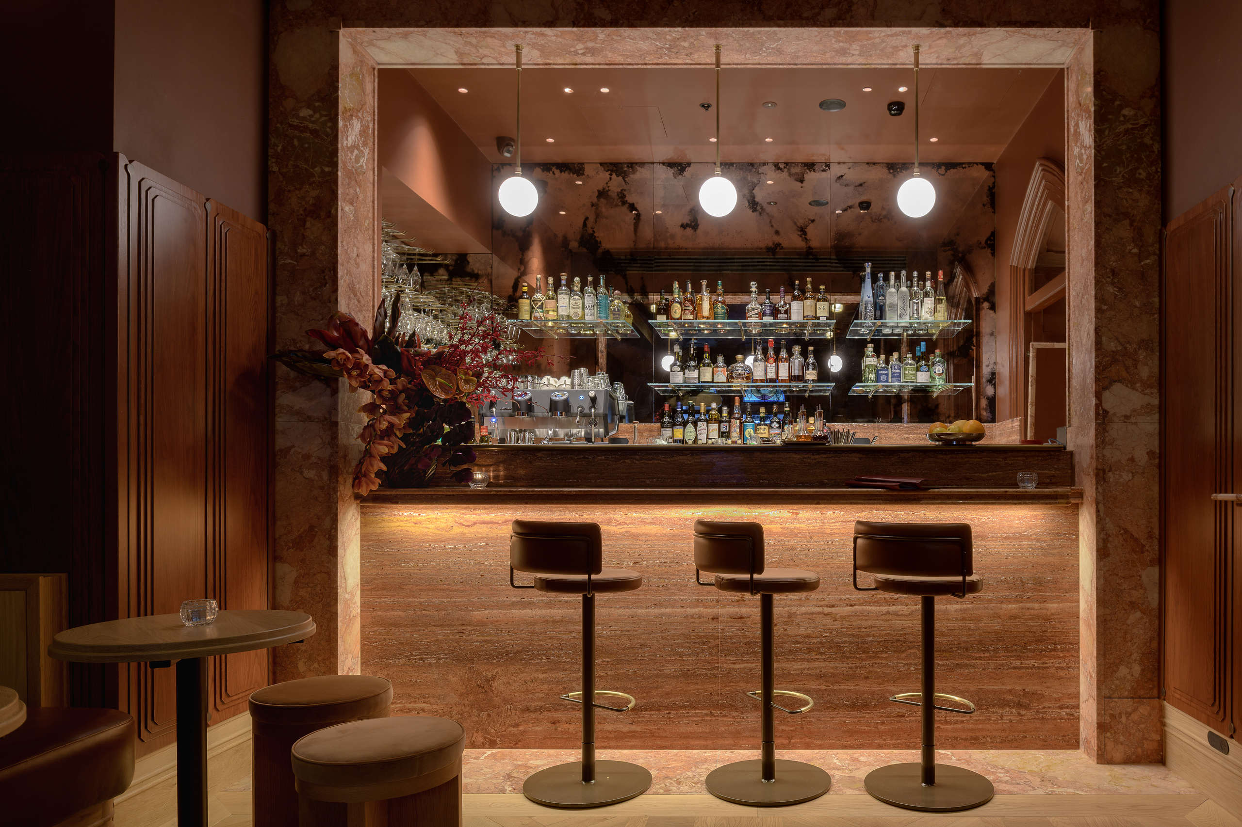 Bar Privé cocktail bar with bespoke stone counter and illuminated bottle display and stools