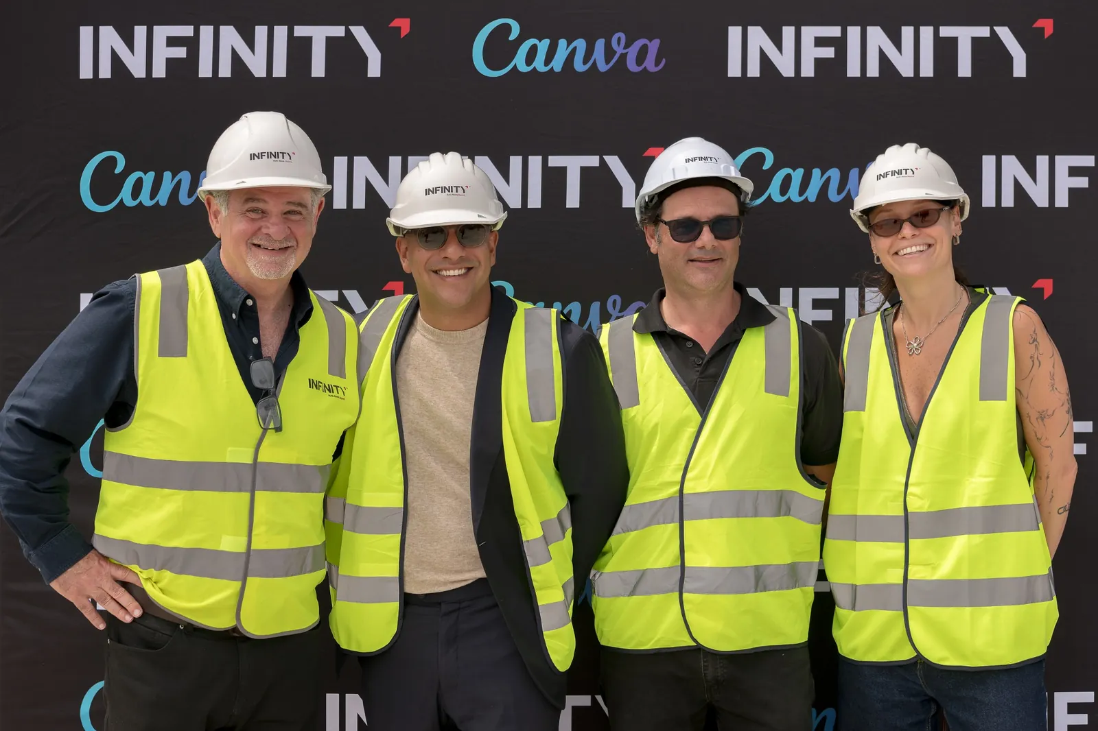 Infinity Constructions and Canva event team posing in front of the branded backdrop
